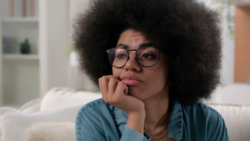 Sad upset female face pensive anxiety thoughtful looking thinking pondering idea solving problem deep in thoughts African American woman girl suffer of loneliness depression at home unhappy stress Royalty-Free Stock Footage #1104231475