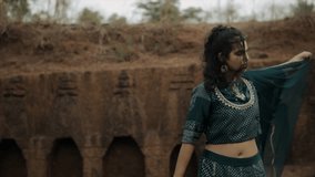 Indian woman in purple indian lehenga choli dress and shawl swings arm in ruins - Powered by Shutterstock - Get 15% off with code: PIKWIZARD15