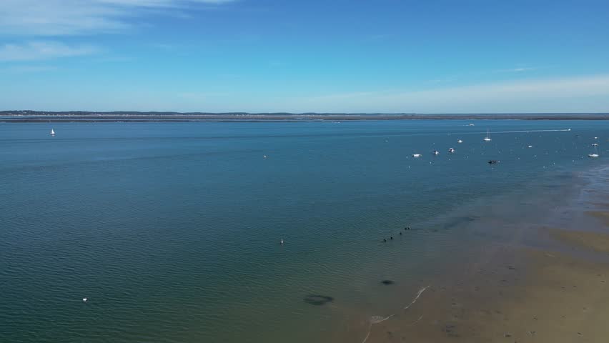 People walk exercising in shallow sandy waters with wetsuits at Arcachon Bay France, Pan left shot
