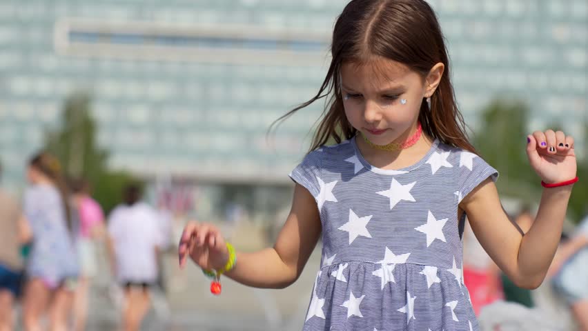 Cute girl playing with a stream of water. Children play at the fountain, close-up. Water fountain in the city park