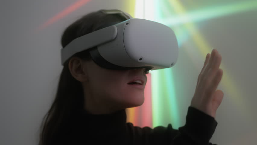 Young woman explores cyber space using vr headset and touches unreal objects. Portrait of female gamer enjoying playing virtual reality game admiring beauty of digital 3D environment
