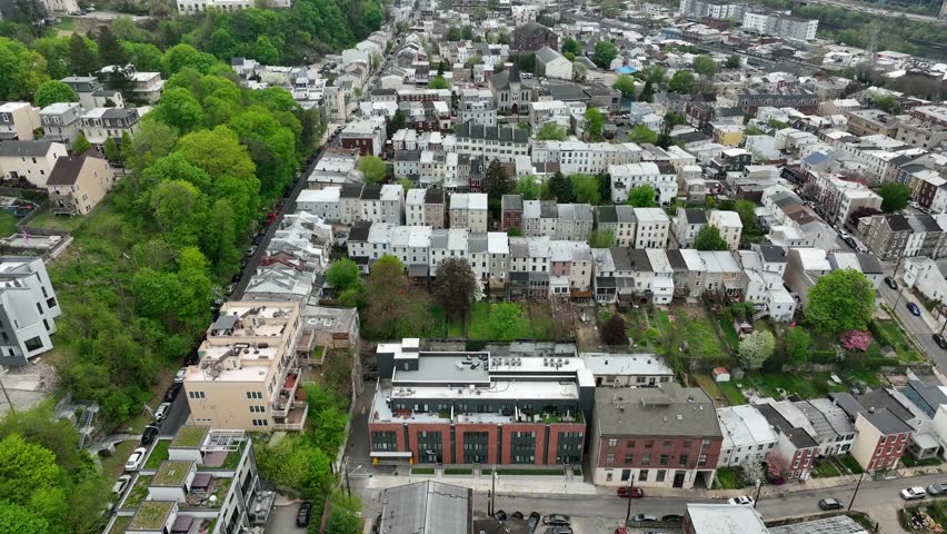 Aerial view of housing in neighborhood. Row houses in city suburb in spring. USA architecture and infrastructure. Tilt up reveal of city skyline on cloudy day.