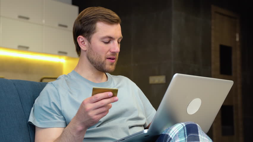 Happy man doing online shopping through credit card at home