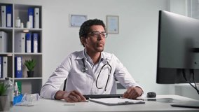 professional black doctor consults patients via video communication on computer using a webcam showing them x-rays while sitting in medical office