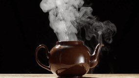 Hot steam rise from brown teapot as boiling water is poured inside, close slomo - Powered by Shutterstock - Get 15% off with code: PIKWIZARD15