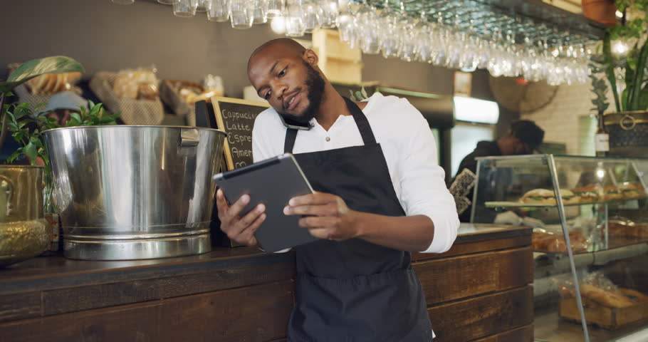 Cafe, order and a black man on a phone call with a tablet for restaurant stock, service and networking. Talking, waiter and an African barista or manager speaking on a mobile with tech for an email Royalty-Free Stock Footage #1104246077