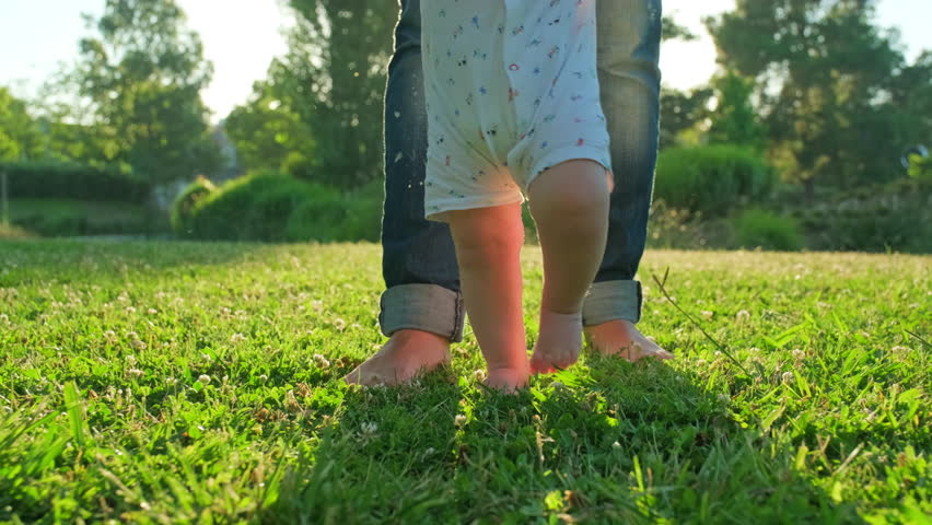 Walking children's bare feet on a green lawn close-up. Child  learns to take the first steps.  Baby learns to walk with the help of his mother on a green grass in the park. Slow motion 4k video. | Shutterstock HD Video #1104247137