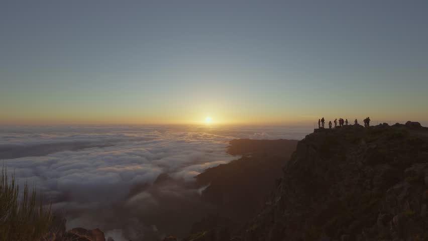 Silhouette of hikers standing on mountain Pico do Ariero at sunrise