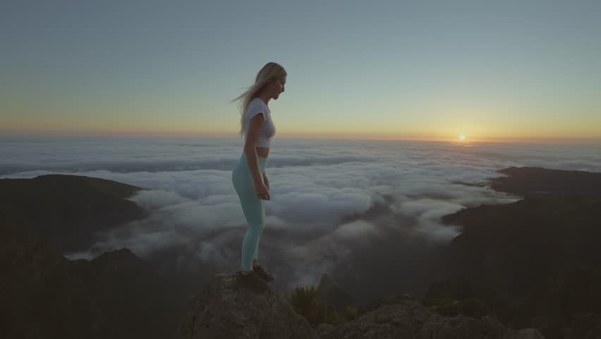 Brave woman jumping onto rock at mountain summit during sunrise, Madeira Royalty-Free Stock Footage #1104254555