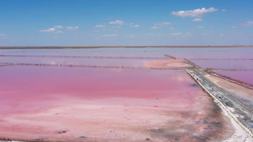 Above pink salt lake with microalgae Dunaliella salina. Famous for its antioxidant properties, enriching water by beta-carotene, used in medicine, dermatology and spa. Salt production facilities pond. Royalty-Free Stock Footage #1104255435