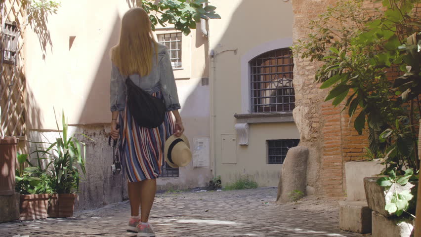 Young blonde woman with blue eyes walking in typical alley in historical neighborhood Trastevere in Rome, Italy. Royalty-Free Stock Footage #1104256961