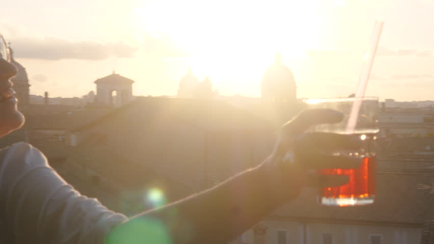Young woman tourist in fashion white dress with spritz cocktail in front of panoramic view of Rome cityscape from campidoglio terrace at sunset. Landmarks, domes of Rome, Italy. Royalty-Free Stock Footage #1104256977