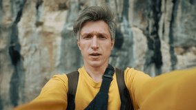 happy smiling man takes a video selfie against a background of beautiful blue rocks, A man travels to picturesque places of the world, Rocks of Turkey, Rock climbing in Turkey.