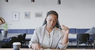 Serious african american casual businesswoman looking at documents during video call, slow motion. Business, communication, office and work, unaltered.