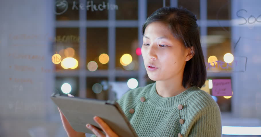 Asian casual businesswoman using tablet presenting to colleagues at night in office. Business, ideas, presentation, office, teamwork, deadline and working late, unaltered.