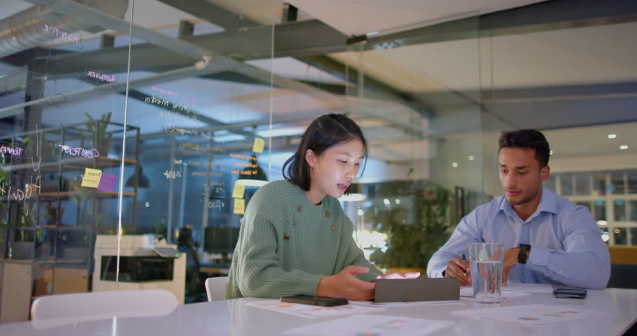 Focused diverse male and female colleague discussing work and using tablet late at office. Business, communication, office, teamwork, deadline and working late, unaltered.
