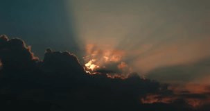Beautiful time lapse, sun's rays shine through dark storm cloud in the sky. Cinematic video of sky, sun peeks out from behind large cloud and illuminates the sky in evening or morning. Hope concept