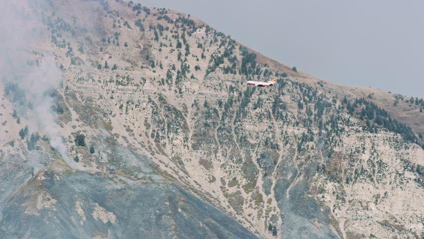 Airtanker flies past wildfire smoke on Wasatch Mountains on its way to refill