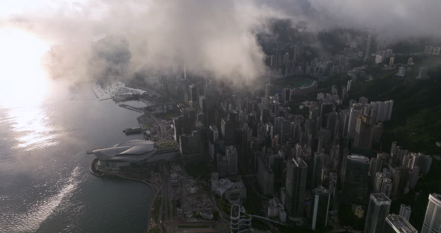 Aerial panning shot of Wan Chai district under low clouds during sunrise. Hong Kong Island