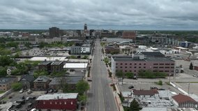 Drone timelapse video moving forward of downtown Lansing, Michigan skyline and Michigan state capitol building along Michigan Avenue on a cloudy day.