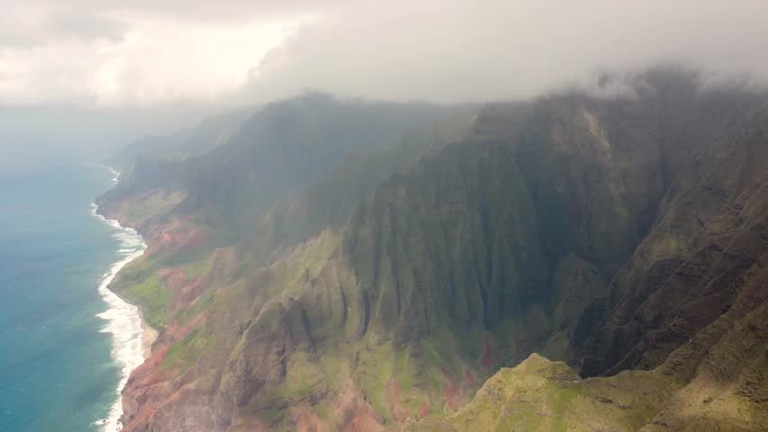 Cinematic Aerial view of Napali Coast Kauai island Hawaii USA with dramatic mountains, blue ocean . Drone flying over green jungle mountain peaks revealing tropical beach on Na Pali park. | Shutterstock HD Video #1104277241