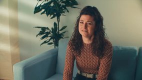 A brown-haired woman on a blue therapy office sofa is crying, symbolizing the challenges of opening up. For mental health campaigns, fostering dialogue, and destigmatizing vulnerability
