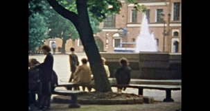 Beautiful Europe city street in summer day. People walk, relax in old city. City life. Green trees, fountain in historic center. Vintage color film. Travel archive. Retro 1980s Vilnius, Lithuania