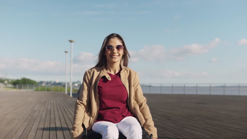 Togetherness and support. Cheerful woman with lower body disability with sunglasses riding with boyfriend outdoors in park