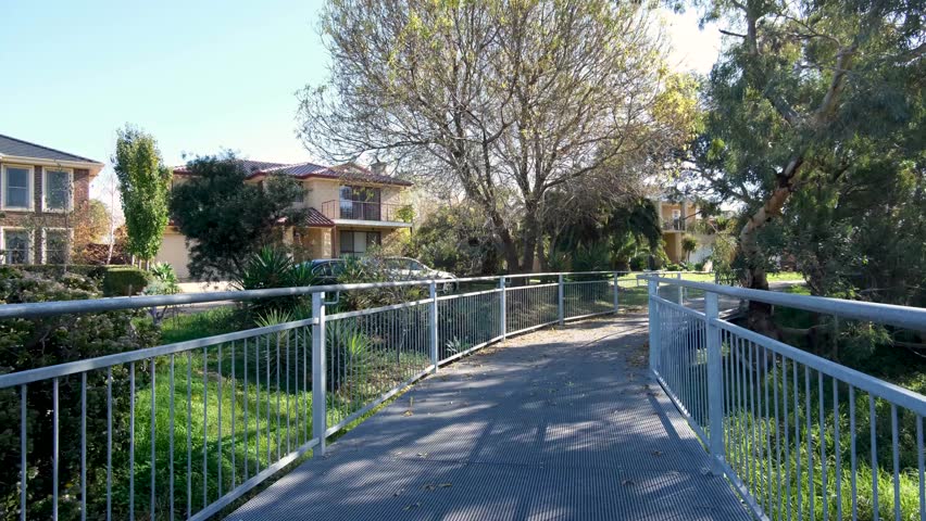 Boardwalk footpath and cycling trail near some residential houses in a Melbourne’s suburban neighbourhood with trees and wetlands.  Beautiful natural environment in neighbourhood in Australia.