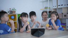 Educational concept of 4k Resolution. kindergarten teacher teaching children using tablet in classroom.