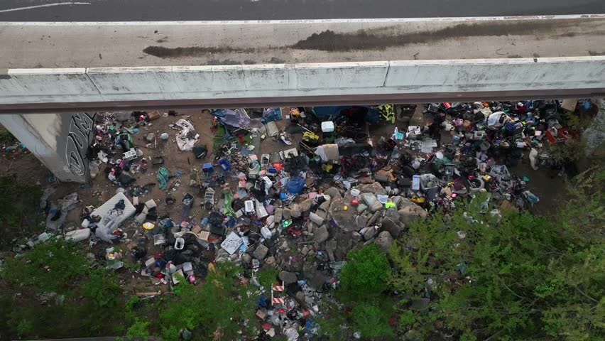 Trash under overpass of highway in urban city. American homelessness and littering theme. Royalty-Free Stock Footage #1104282515