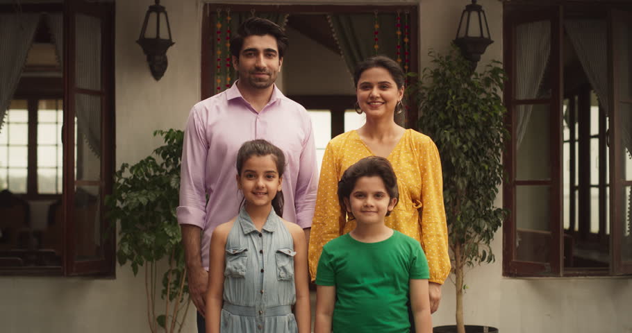 Portrait of Happy Indian Nuclear Family Looking at Each Other and Posing Together. Gorgeous Parents and Their Cute Two Kids Looking at the Camera, Happy in Their Newly Purchased Home. Zoom in Royalty-Free Stock Footage #1104284189