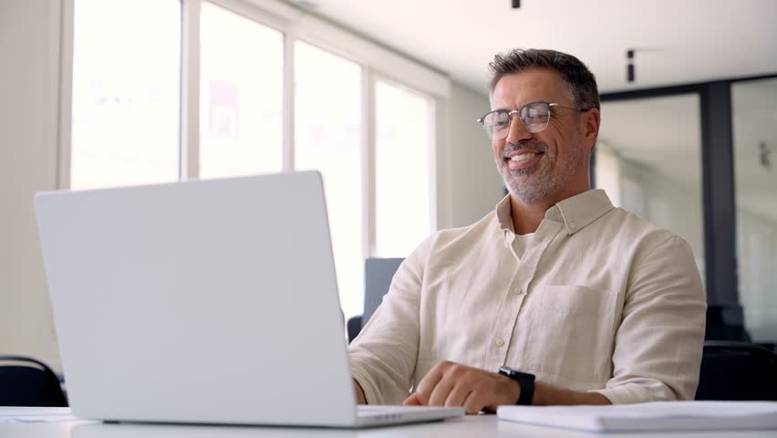 Middle-age Hispanic man using computer remote for business studying, watch online virtual webinar training meeting, video call. Smiling mature Indian or Latin businessman working on laptop in office. Royalty-Free Stock Footage #1104284993
