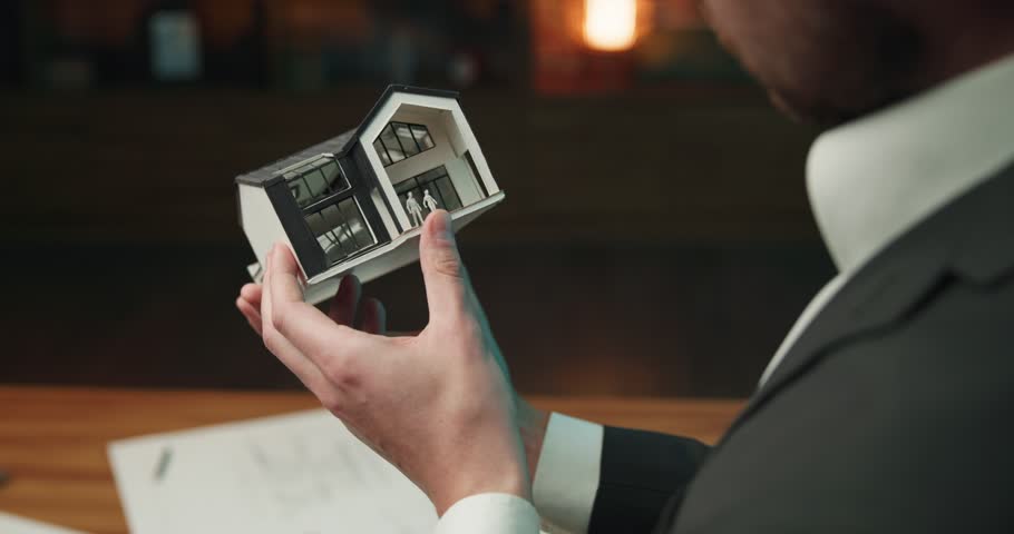 Over the shoulder shot of an architect working on a building layout. Young male engineer with glasses on looking at a house layout in his hands