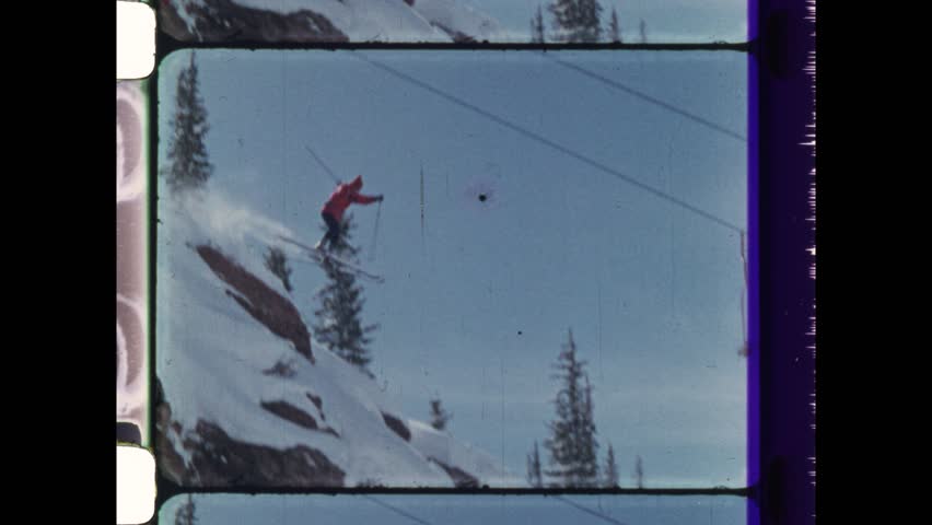 1983 Copper Mountain, CO. Daredevil man jumps off cliff on ski slope and crashes into powder skis snow. Skier performs big jump on ski slope. 4K Overscan of Vintage Archival 16mm film 