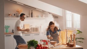 Happy couple cooking together and have fun throwing flour at each other. A woman and a woman making mess in the kitchen smiling laughing. Family have fun while preparing pasta - Powered by Shutterstock - Get 15% off with code: PIKWIZARD15