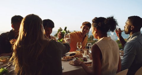 Group, friends and outdoor dinner at sunset and drinks, food and wine for people together for rooftop meal in nature. Women, men and diverse summer party, happy celebration or reunion of friendship స్టాక్ వీడియో
