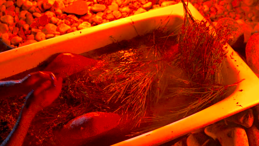 Outdoor bathtub stands under the stars. Water with medicinal herbs is heated by fire, and torches illuminate the surroundings. A man bathes in it