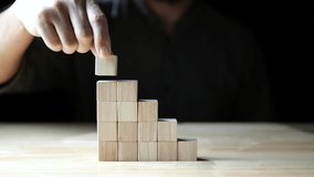Close up businessman hand building wood blocks as steps stair on dark background, business development, business growth, success. Business growth, financial plans, investments, and strategies - Powered by Shutterstock - Get 15% off with code: PIKWIZARD15