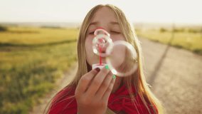 Teen girl blowing soap bubbles in field at sunset time.