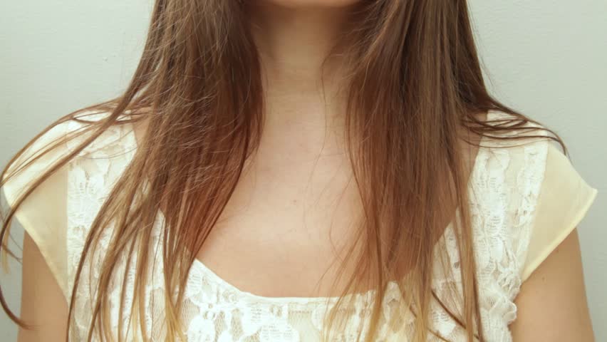 Caucasian woman in a vintage white dress putting on a bronze color necklace. Close up of a retro style lady getting ready to go out.