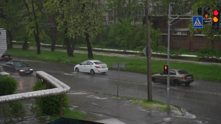 Cars at the crossroads in heavy rain. Slow motion