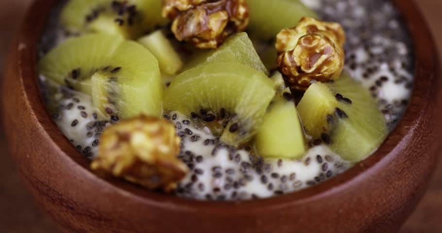 Fresh yogurt with kiwi flavor and with pieces of fruit, chia seeds and popcorn, delicious fresh yogurt with the addition of pieces of ripe yellow kiwi with chia and popcorn | Shutterstock HD Video #1104324233