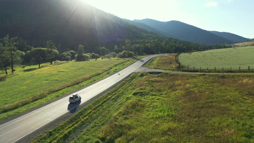 White travel car riding on new asphalt road surrounded picturesque summer mountain scenery river journey aerial view. Drone cinematic minivan car alpine landscape exploration vacation destination 4k Royalty-Free Stock Footage #1104329323