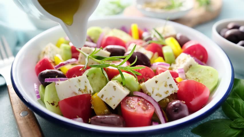 Greek salad. Vegetable salad with feta cheese, tomato, olives, cucumber, red onion and olive oil. Healthy vegetarian mediterranean diet food. Video 4k Royalty-Free Stock Footage #1104329735