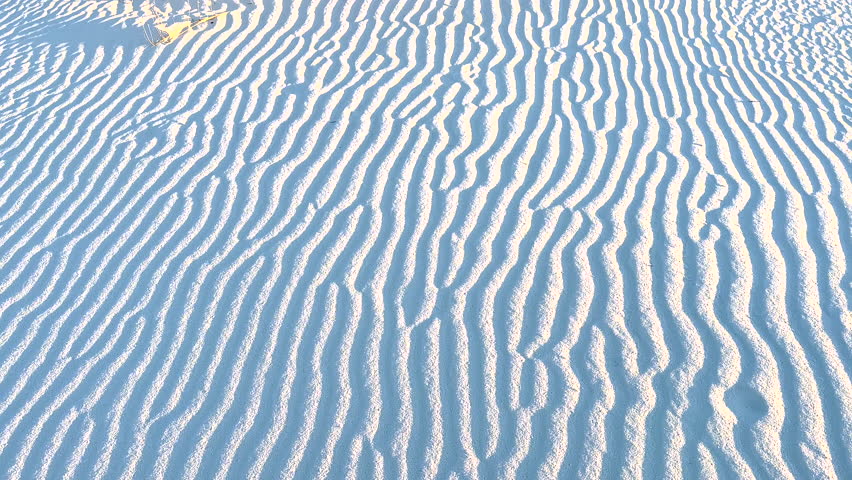 Pan Up Of Ripples In White Sand Dunes To Bushes And Blue Sky in New Mexico