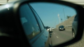 View from the reflection of the side mirror. Blured Cars are driving on the road in the next lane on a sunny day.