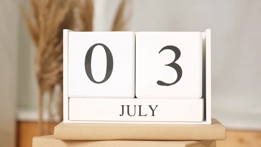 The man puts the date July 4th on the calendar. Wooden calendar with an important event for July 4, USA Independence Day.