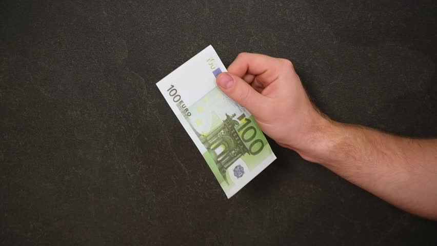 A man sets fire to 100 euros. Crisis. Hand holding burning Euro banknotes