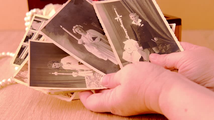 female hands are sorting dear to heart memorabilia in an old wooden box, stack of retro photos, vintage photographs of 1950, concept of family tree, genealogy, childhood memories, home archive Royalty-Free Stock Footage #1104340075
